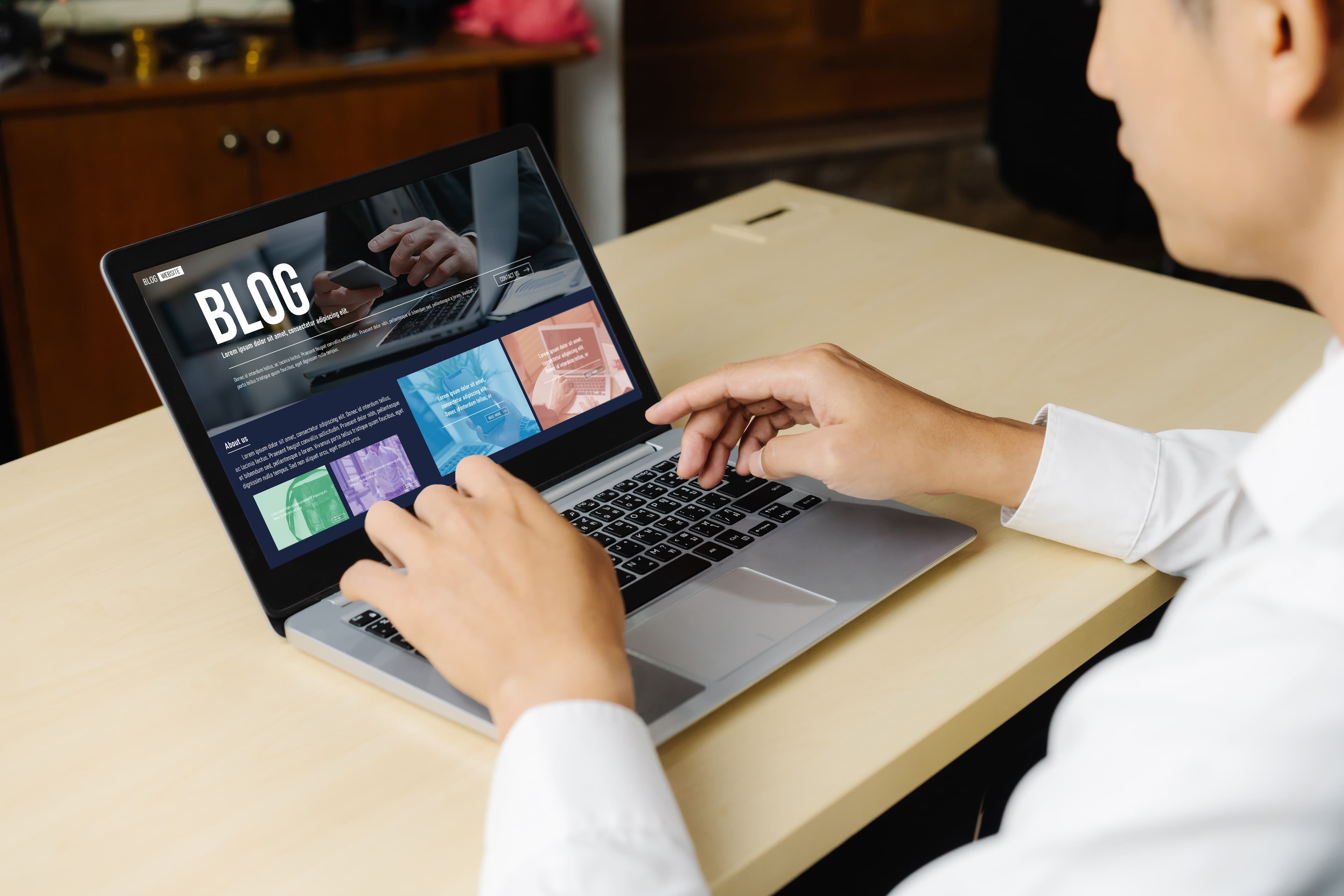 Person typing on a laptop showing a blog website