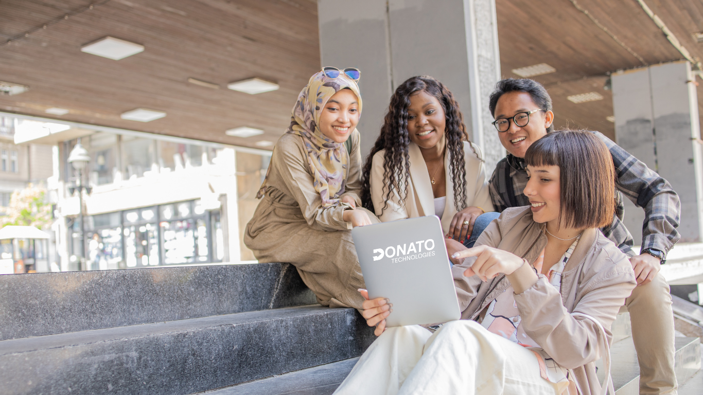 A group of Gen Z professionals sitting on stairs, discussing a tech project and collaborating on ideas for the future workforce.